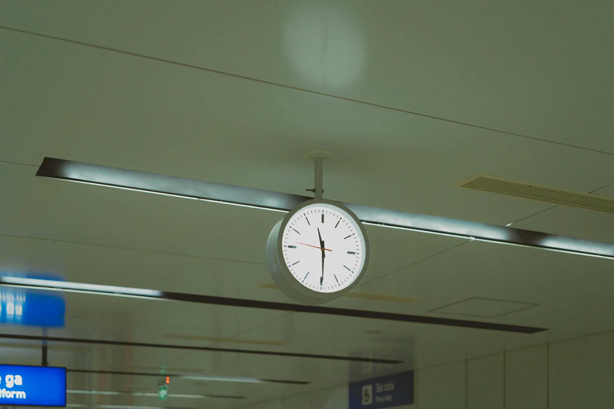 a-clock-hanging-from-the-ceiling-of-an-airport.jpg A clock hanging from the ceiling of an airport